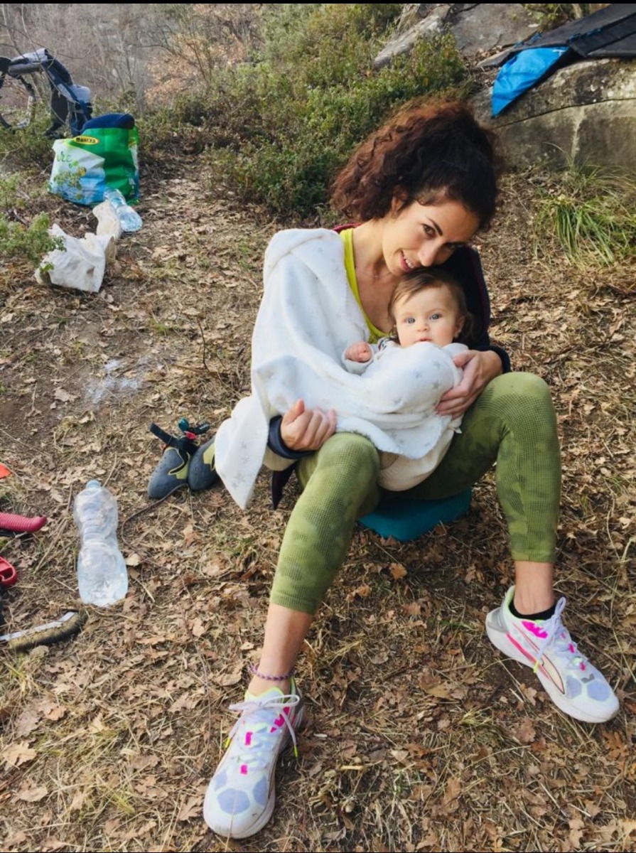 屋外に座り、小さな子どもを抱いている人