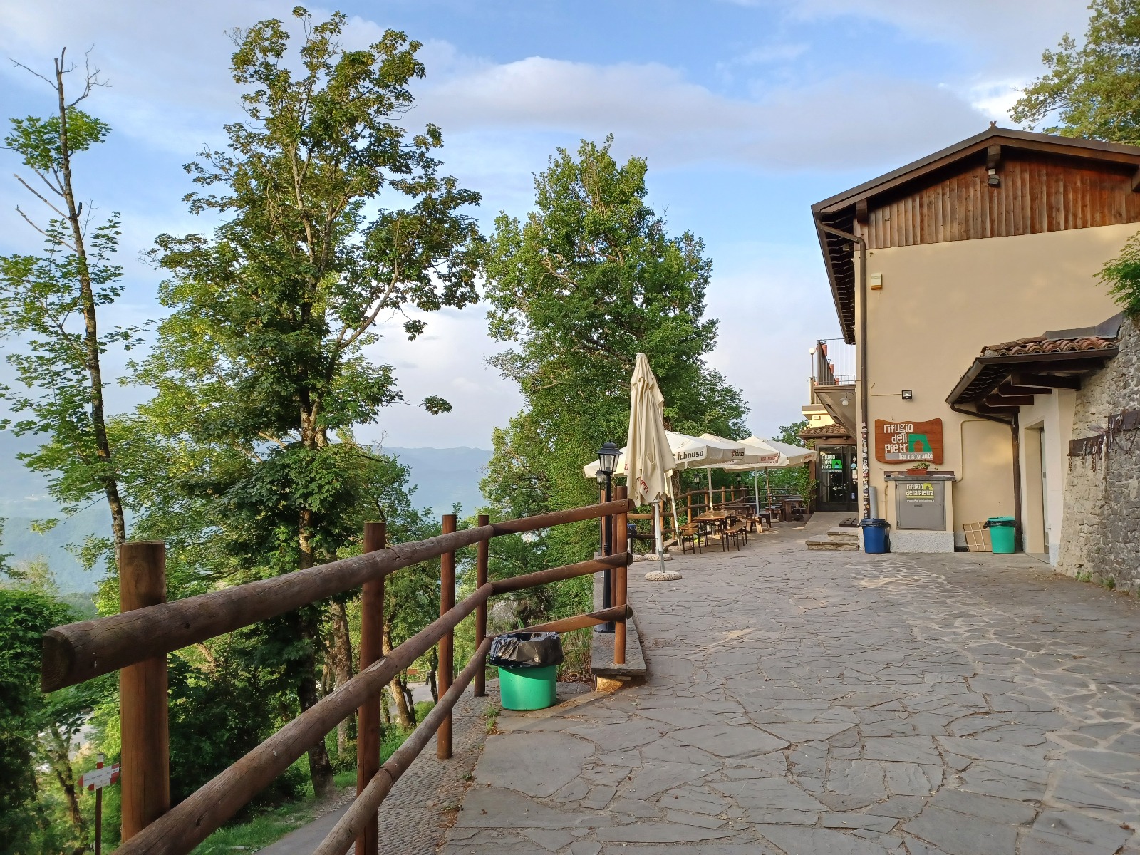 木々の間の石畳の道とRifugio della Pietraの建物