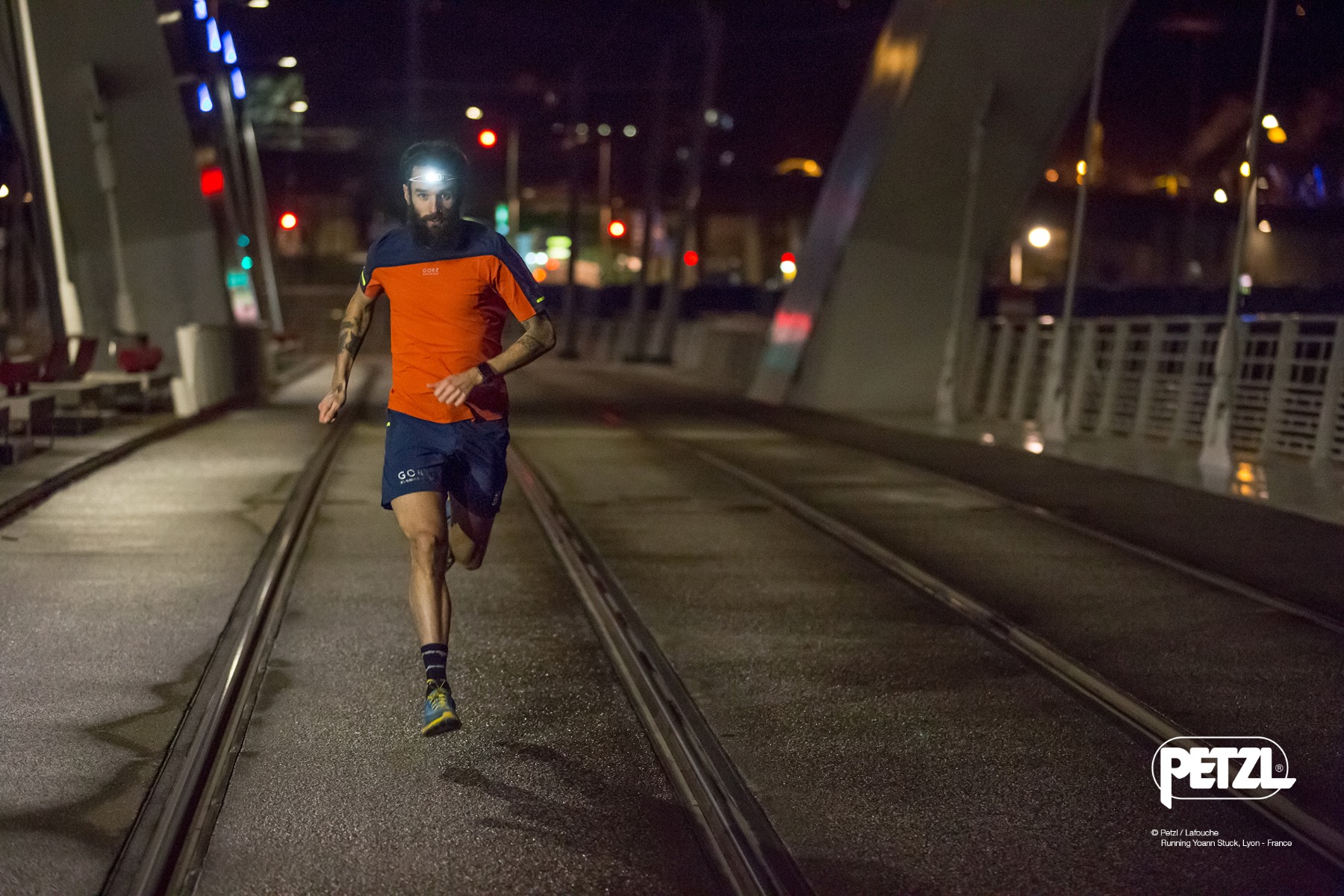夜の市街地の道で点灯したヘッドランプを付けて走る人