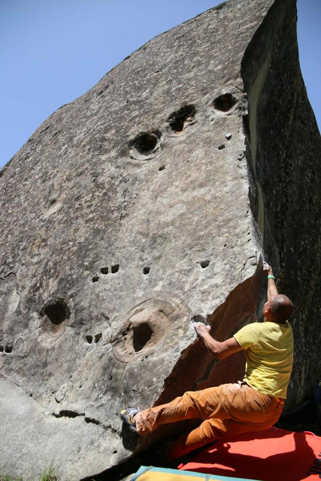 クラッシュパッドの上でAnnotの砂岩ボルダーを登るクライマー