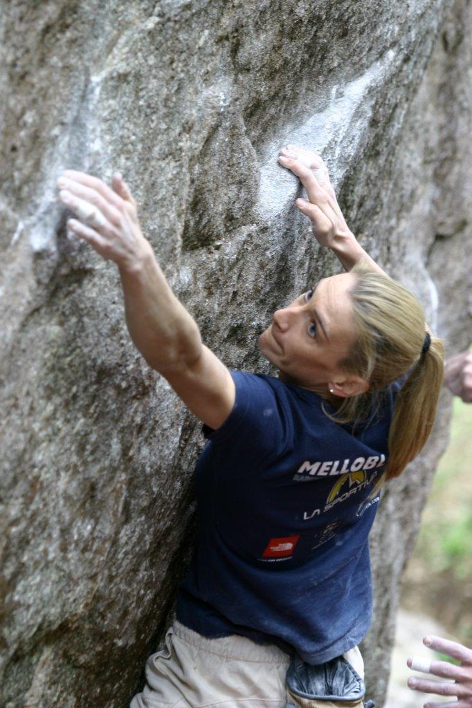 青いシャツを着たOlga Bibikが、花崗岩の岩でホールドを探す