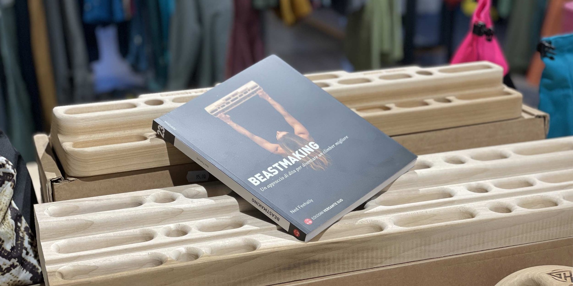 木製フィンガーボードの上に置かれたNed Feehally著『Beastmaking』イタリア語版の表紙