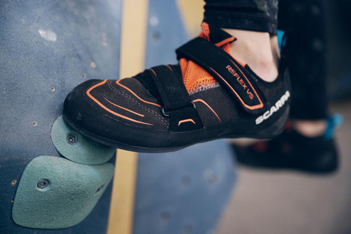 人工壁のホールドに置かれた、SCARPA Reflex のクライミングシューズを履いた足。