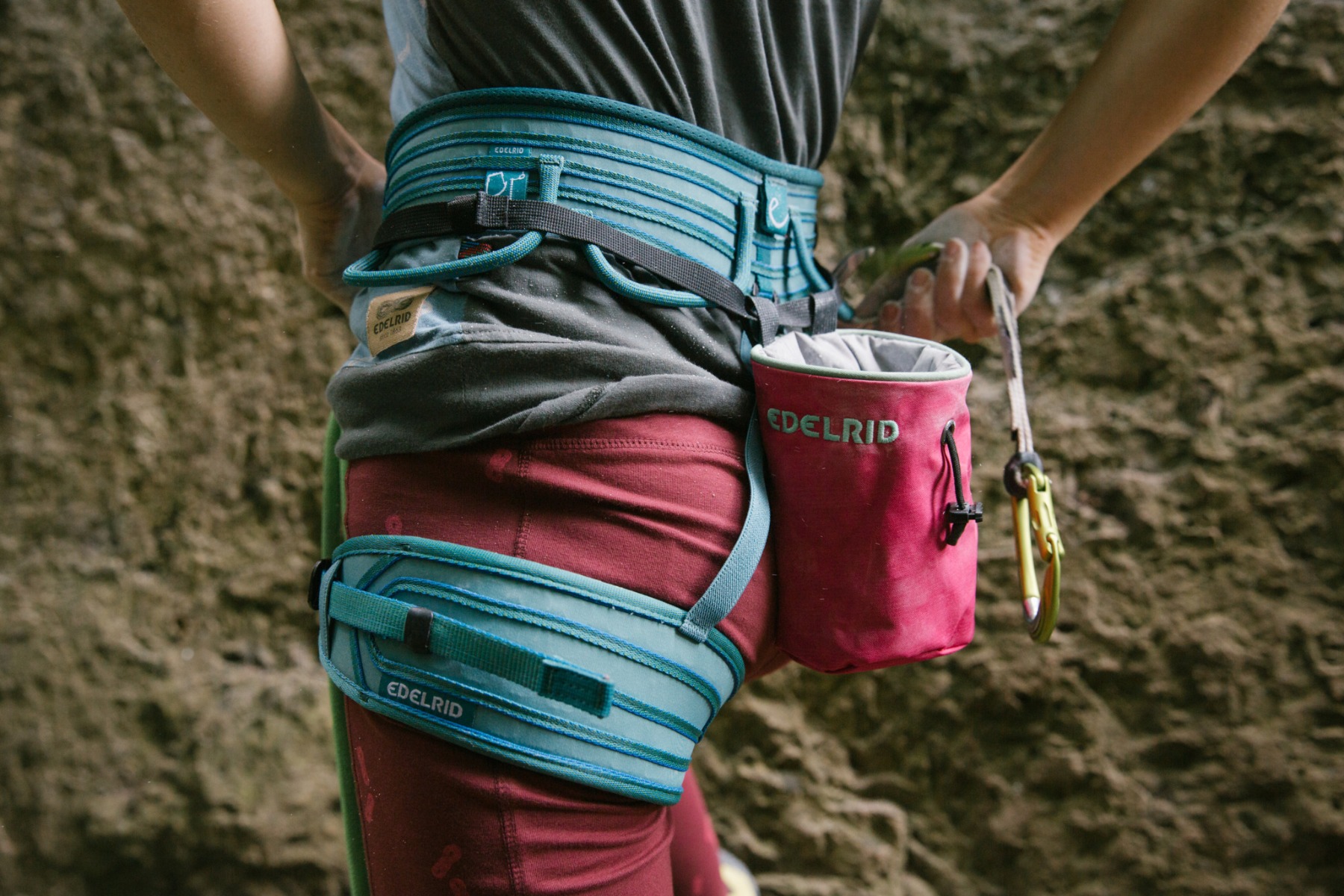 岩壁の前にいる人が着けた青いハーネスと赤いチョークバッグの細部 — Edelrid Medienceter