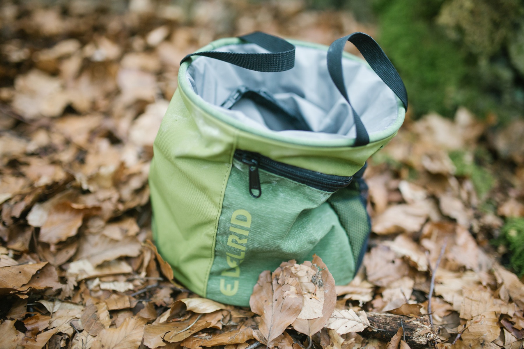 Martin Poetter Edelrid 乾いた落ち葉の上に置かれた大きな緑色のチョークバッグ