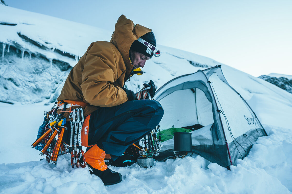 雪の上のテントの隣にしゃがむ人とクライミング用具 — ©MathisDumas- athlete Mathieu Maynadier- location Mont Blanc area