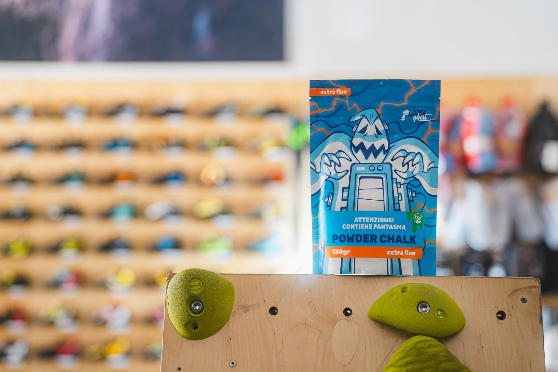 クライミングジムのLazyghost Casperチョーク 屋内クライミングウォールのそばに置かれた青いLazyghost Casper 130 gチョーク袋