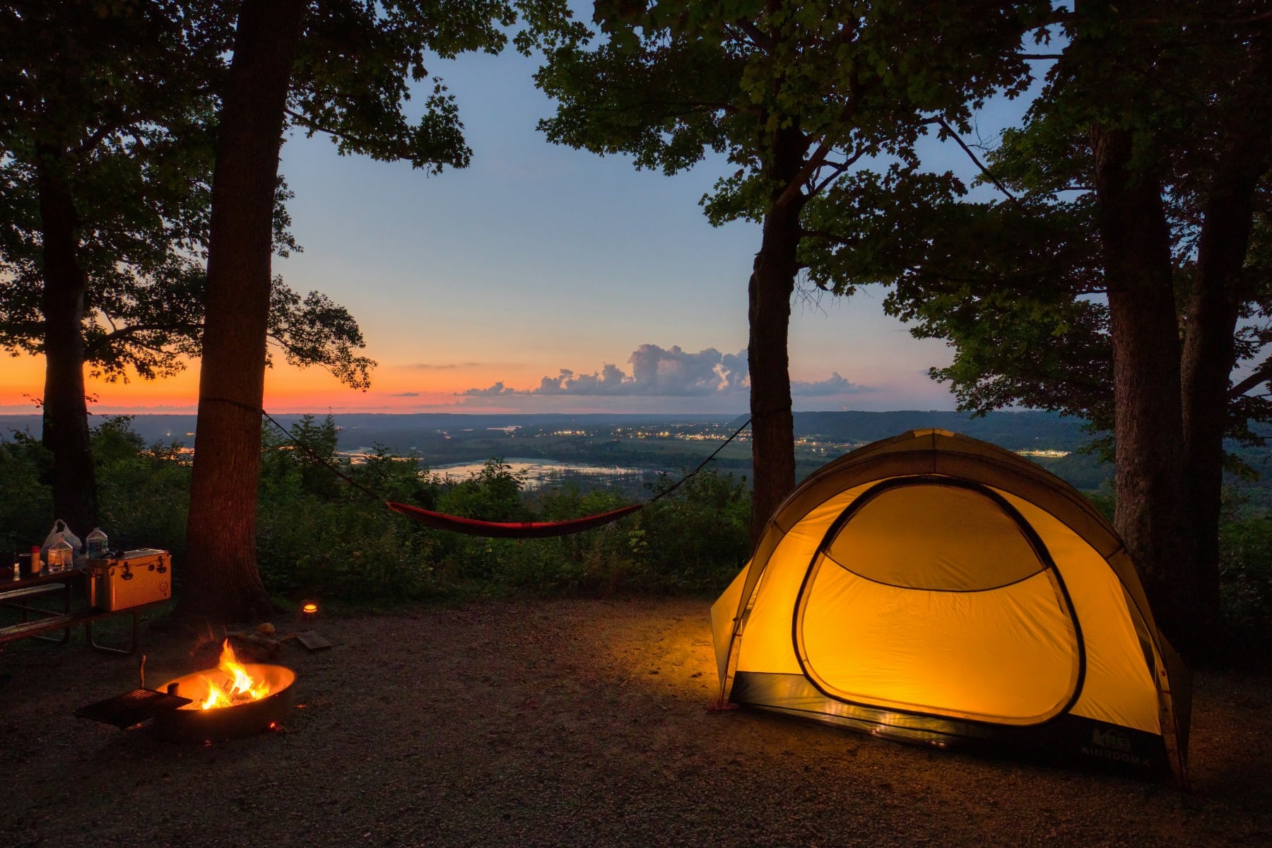 夕暮れのキャンプ用テント、撮影:Dave Hoefler 夕暮れの木々の間で明かりがともるキャンプ用テント