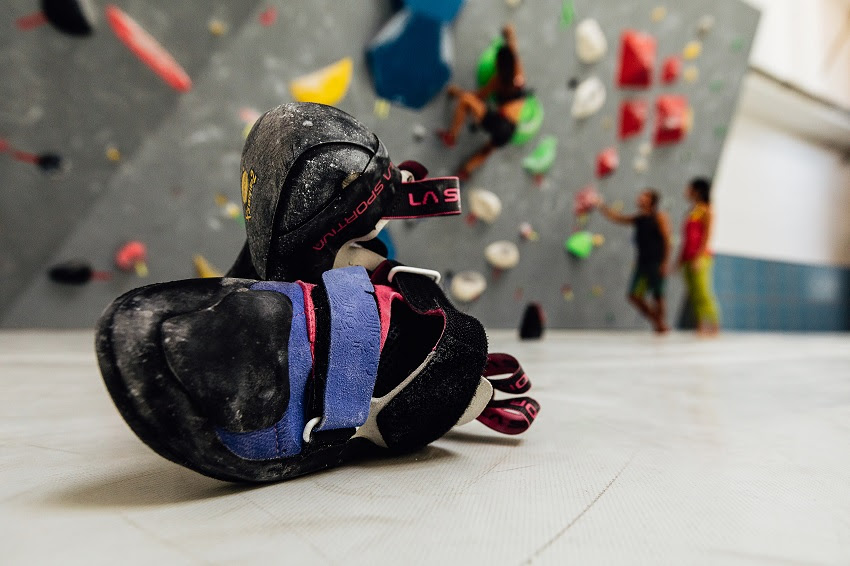 屋内のボルダリング壁の前に置かれたLa Sportivaのクライミングシューズ
