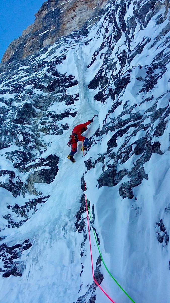 Phoenixの岩壁の間の氷柱を登る赤い服の登山者