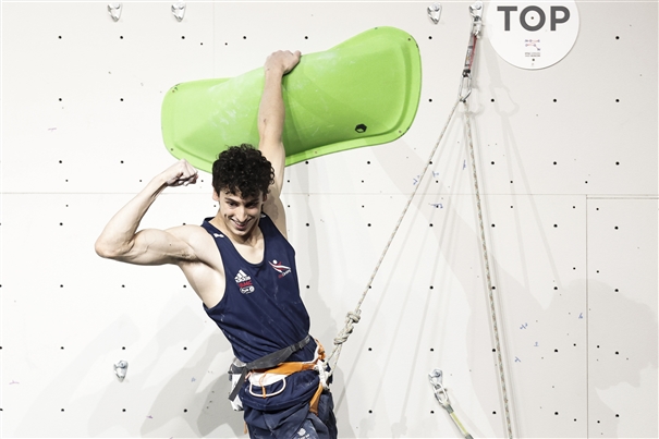 イギリスのユニフォーム、ロープ、ハーネスを着用してルートのトップにいる選手。写真 Dimitris Tosidis / IFSC
