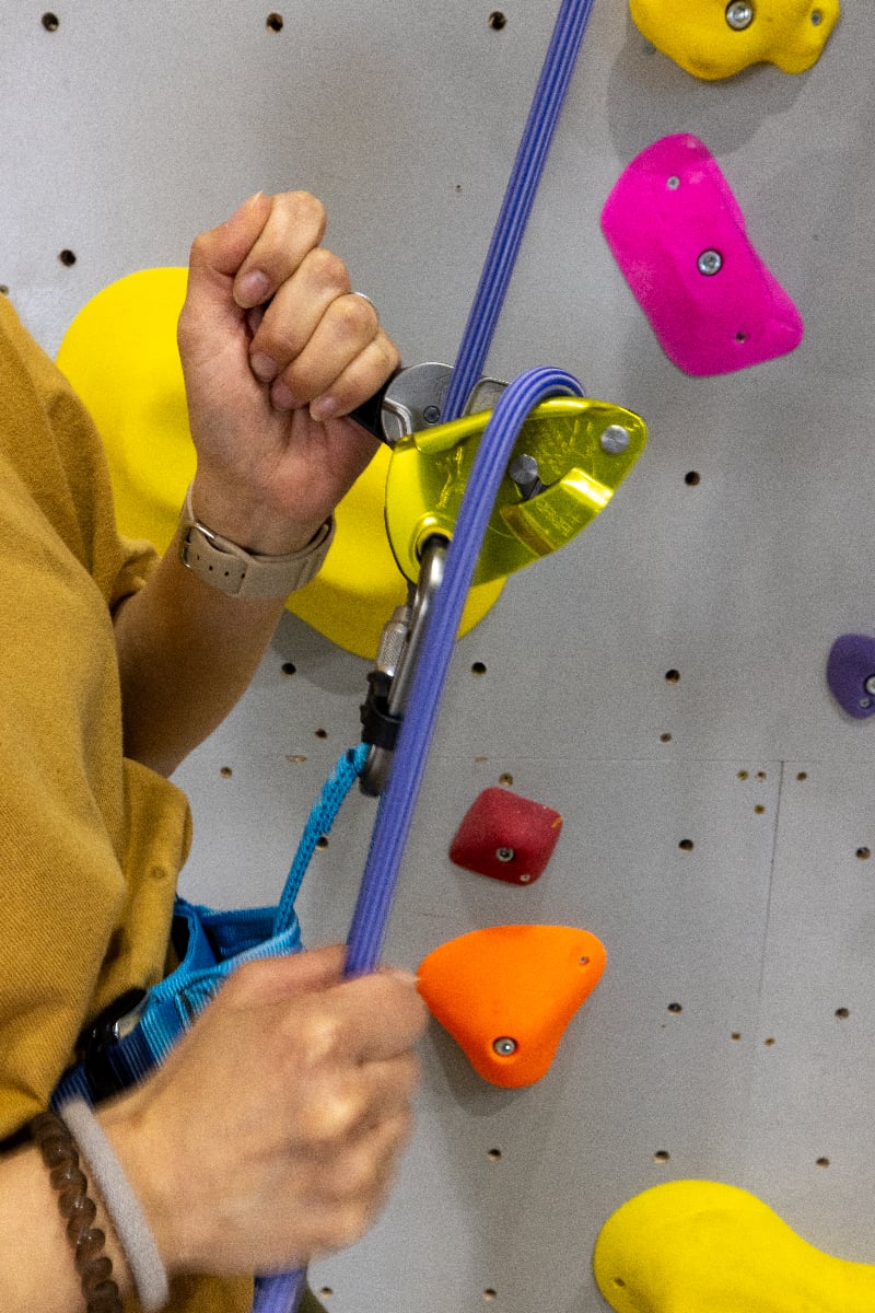 クライミングジムで、黄色いPetzl GriGri+のそばで青いロープを持つビレイヤー