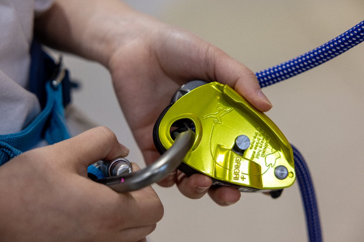 黄色いPetzl GriGri+とロッキングカラビナを持つ手元