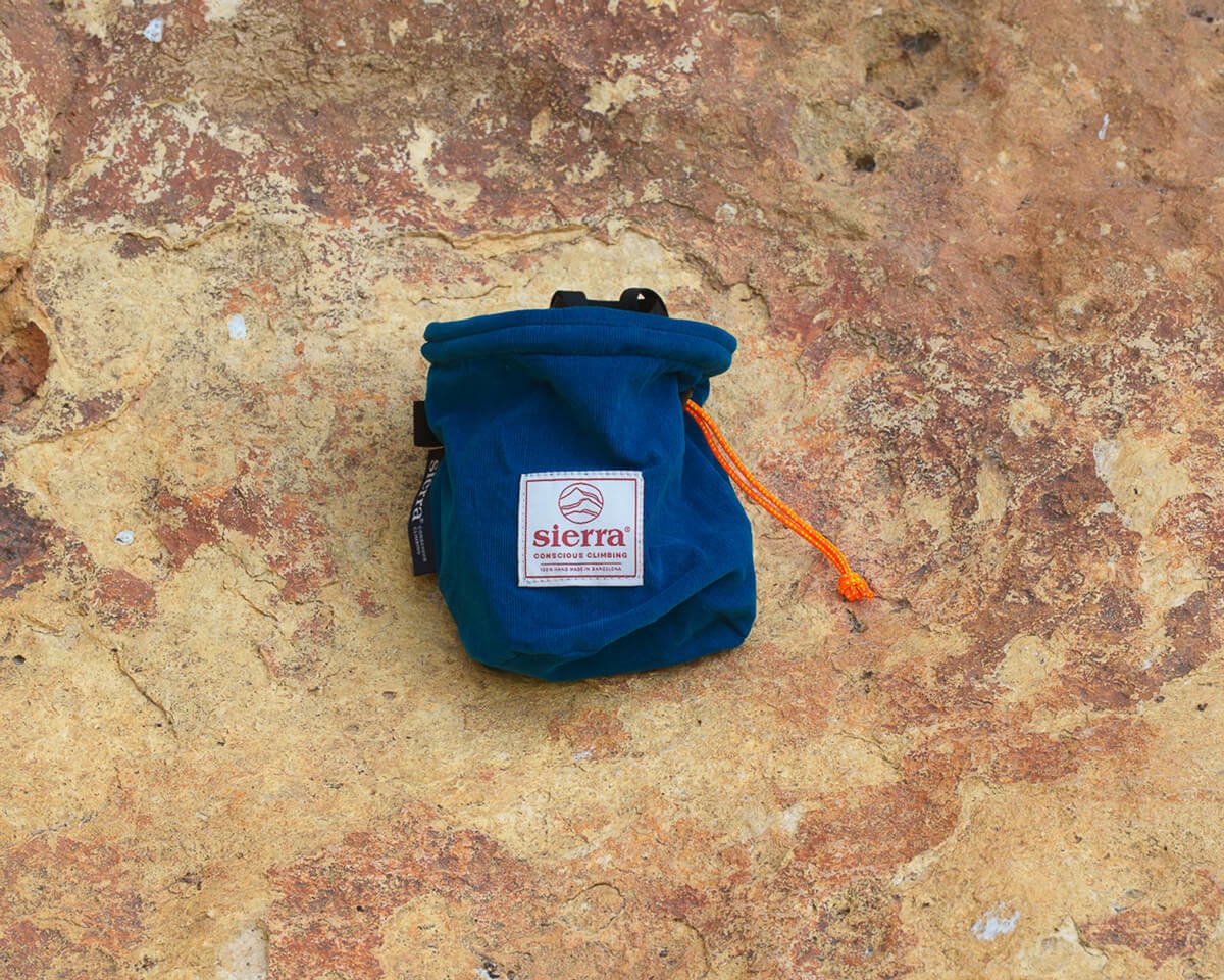 岩の上に置かれた、オレンジ色のコードがある青いSierra Climbingチョークバッグ