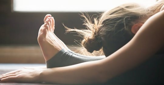 Deb_yoga_climb 前かがみになり、両腕を足のほうへ伸ばしている人